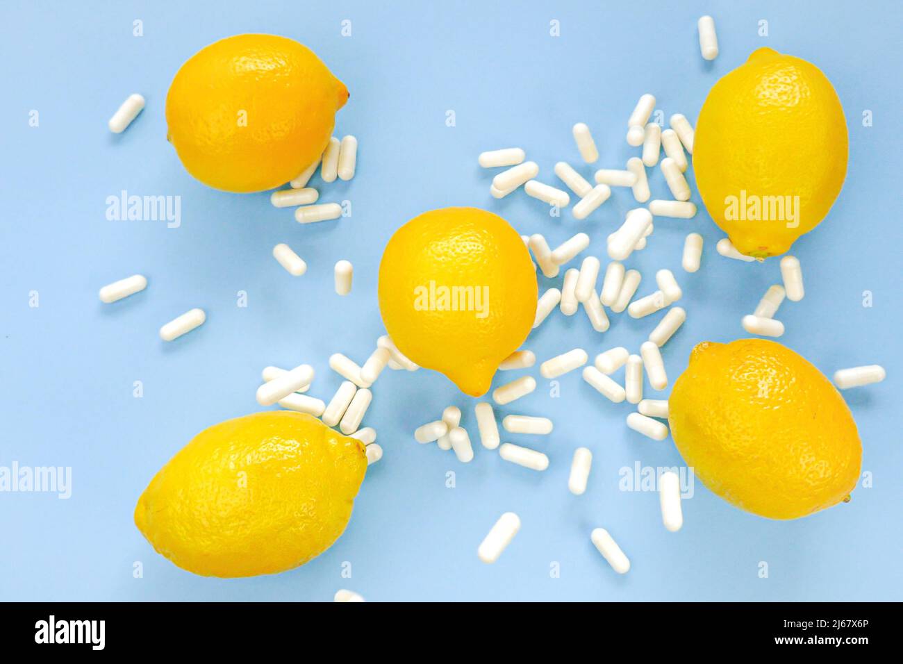 Flying vitamin C white tablets and yellow lemons on a blue background.Natural Fruit Vitamin C