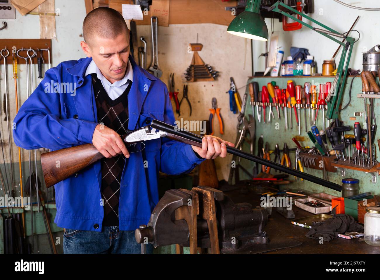 Gunsmith examines an automatic rifle before being repaired in weapons