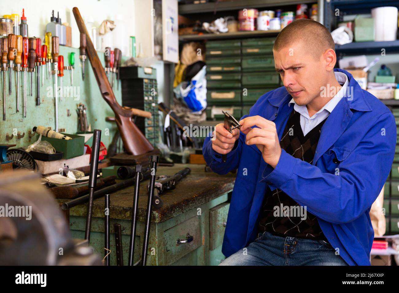 Craftsman of weapons using vernier caliper to measure shotgun