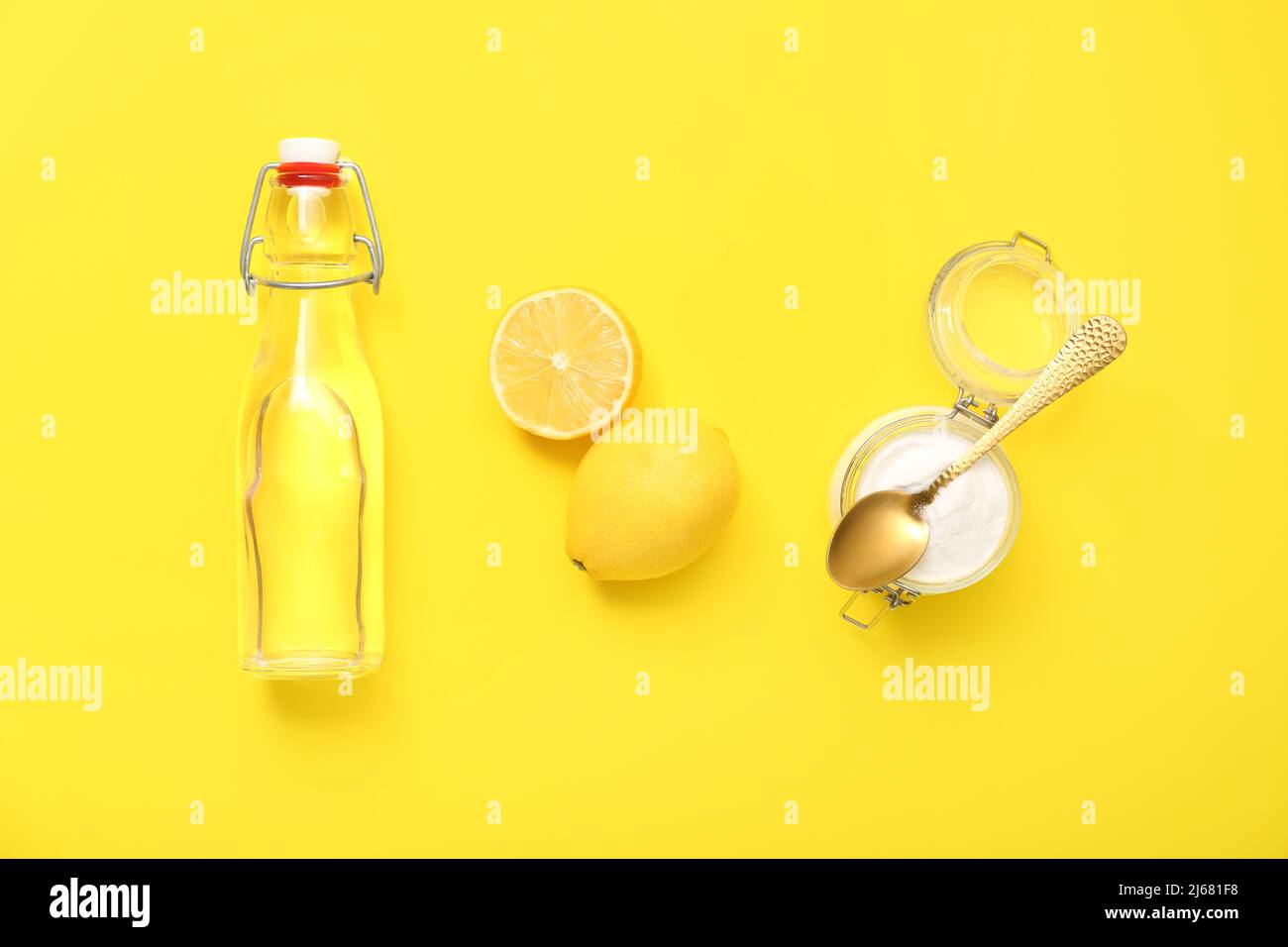 Bottle of water, ripe lemon and jar with baking soda on yellow