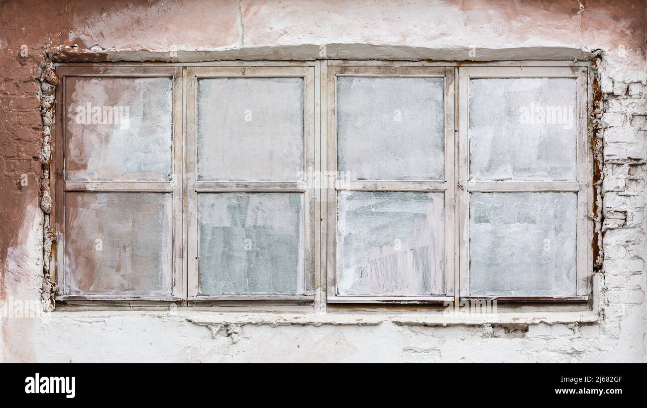 grungy white painted window on rough white plaster wall of industrial building Stock Photo