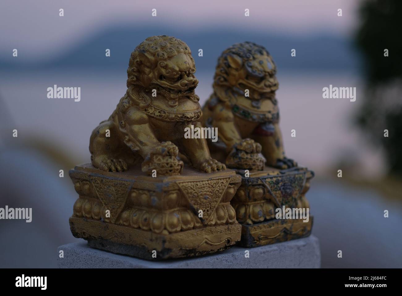 A gold colored statuettes of lavishly decorated lions (or similar mythological creations)  near Buddhist temple in Thailand Stock Photo