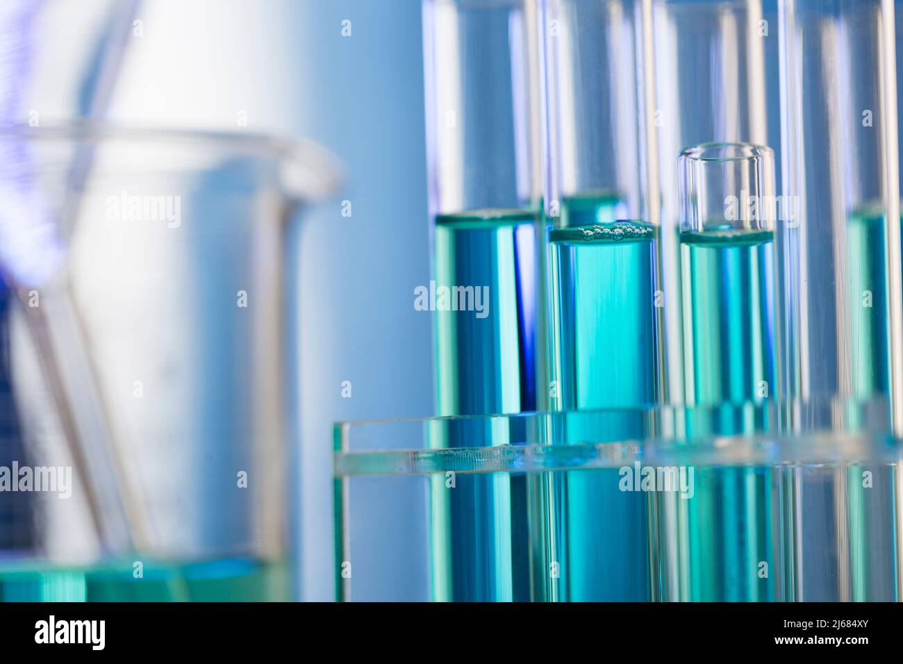 Neatly arranged test tubes containing blue reagent in chemistry laboratory with beaker - stock photo Stock Photo