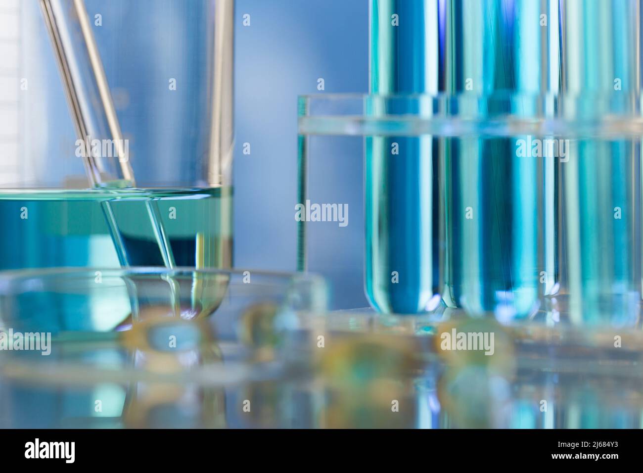 Neatly arranged test tubes containing blue reagent in chemistry laboratory with beaker and soft capsule - stock photo Stock Photo