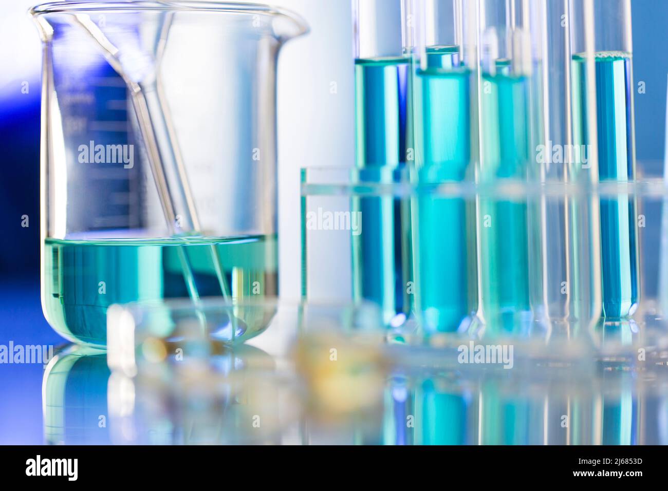 Blue chemical reagent in the beaker with glass funnel and test tube rack - stock photo Stock Photo