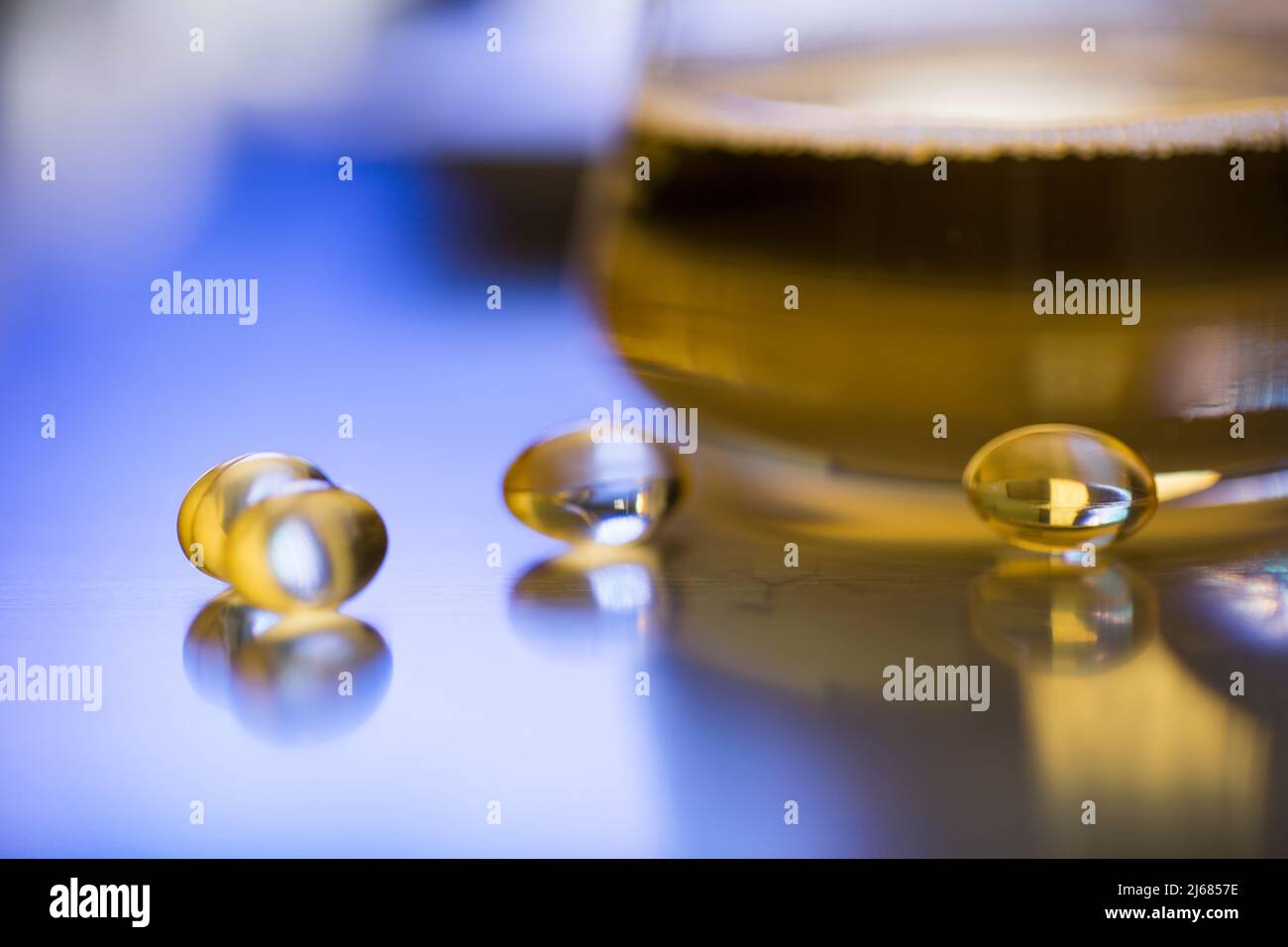Conical flask containing a golden liquid medicine with Soft capsules and funnel - stock photo Stock Photo