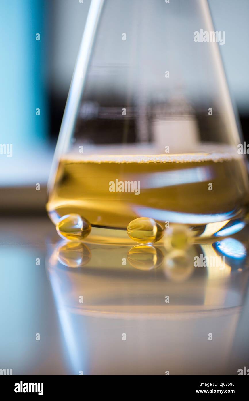 Conical flask containing a golden liquid medicine with Soft capsules