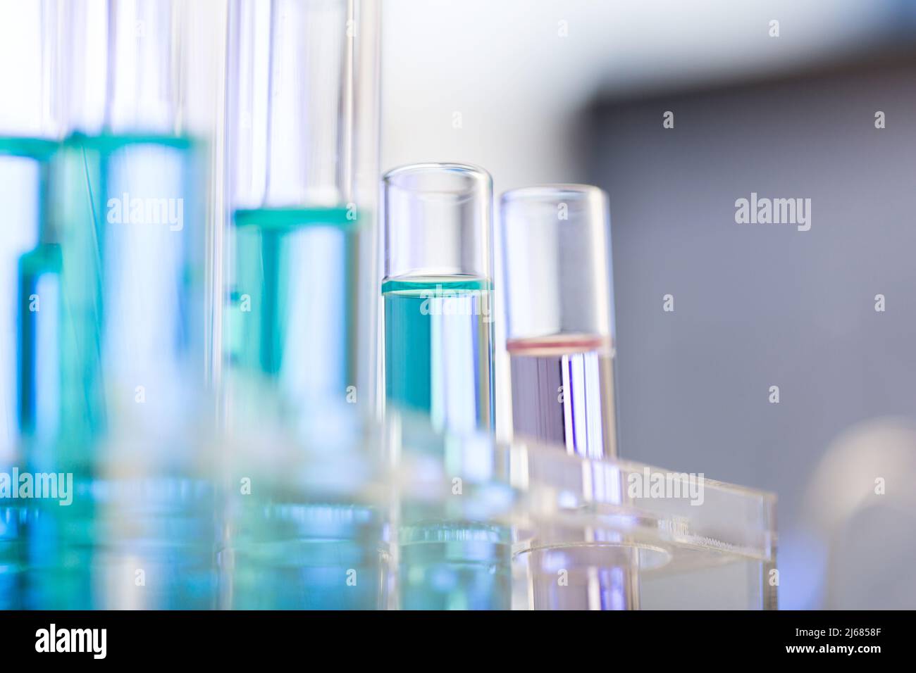 Neatly arranged test tubes containing blue and pink reagent in chemistry laboratory - stock photo Stock Photo