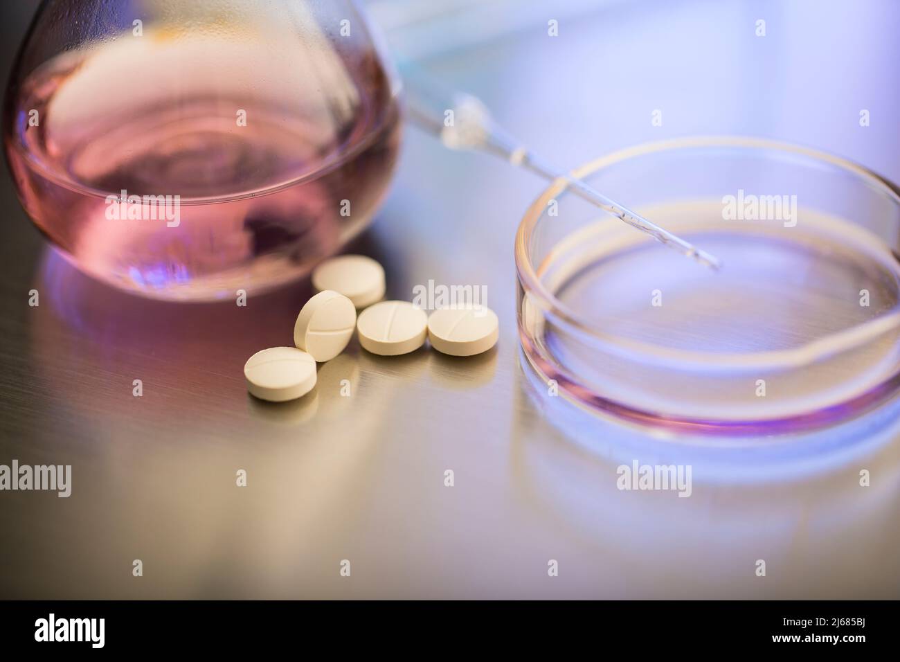 Pale yellow pills from the lab with dropper, petri dish and laboratory flask - stock photo Stock Photo