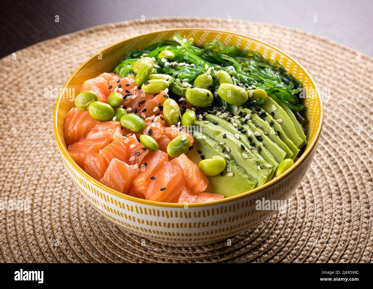 From above of delicious poke bowl with fresh vegetables and salmon placed on table in cafe Stock Photo