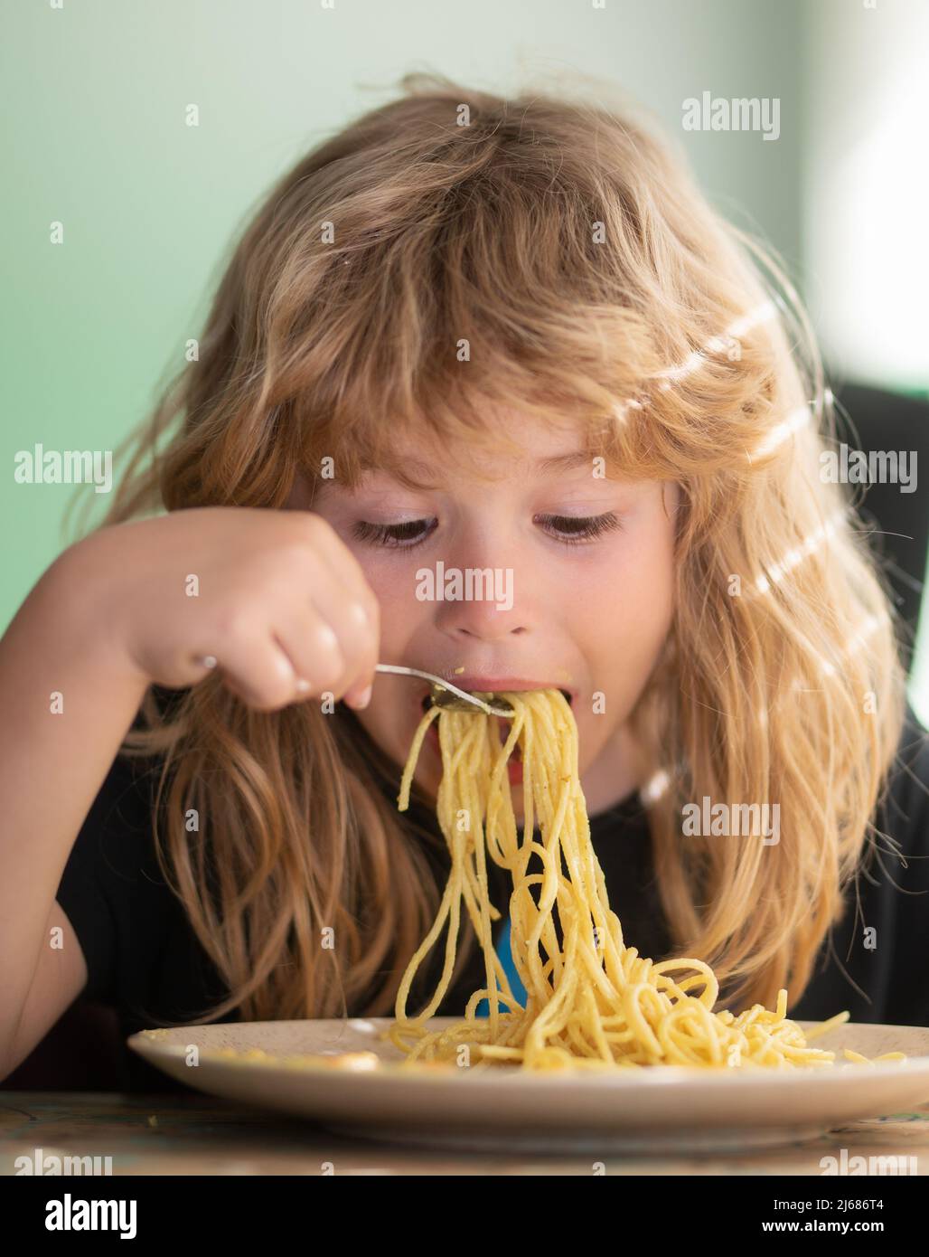 Tasty food, messy child eating spaghetti. Young kid sitting on the