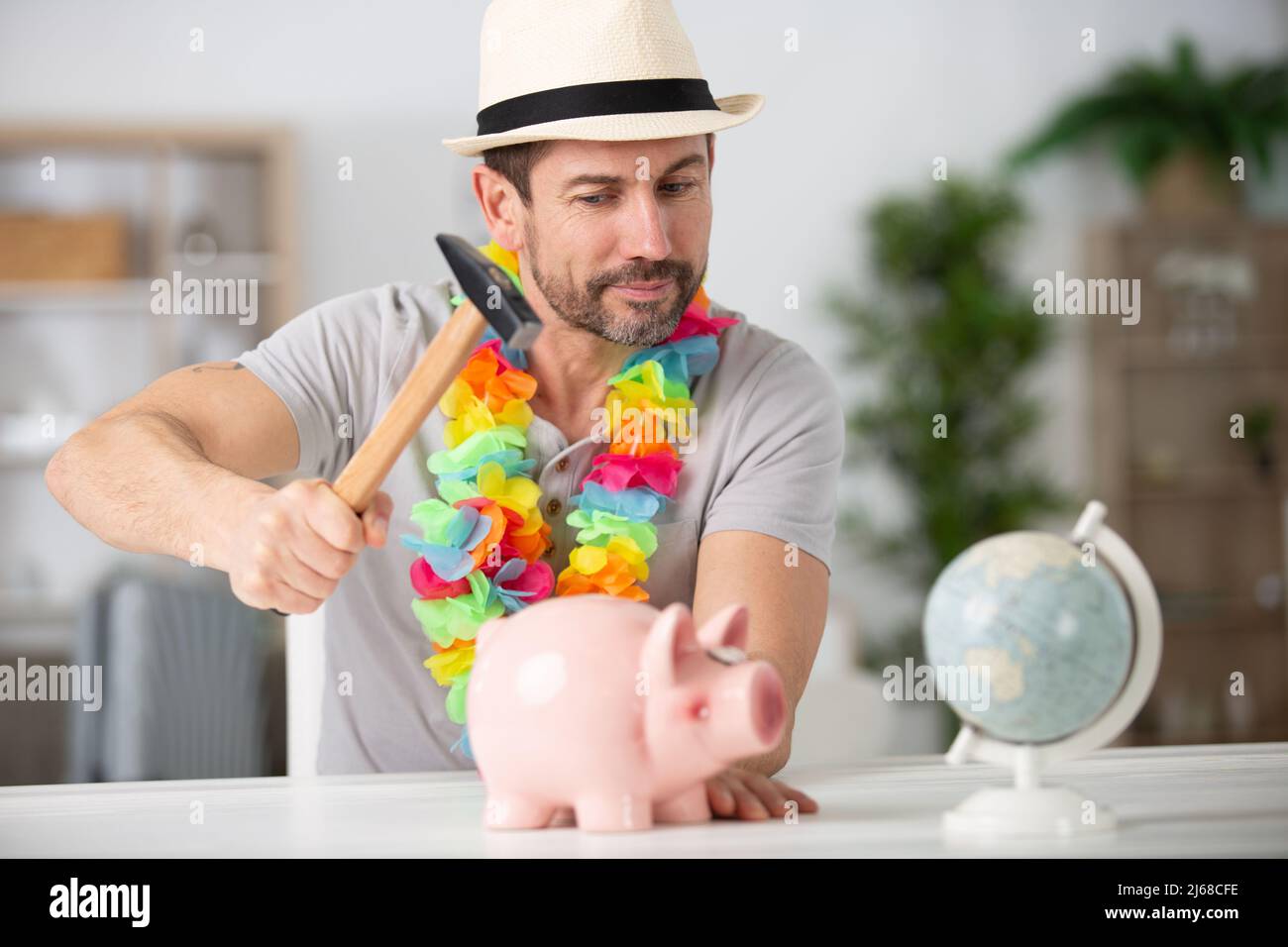man breaking piggy bank with hammer Stock Photo - Alamy