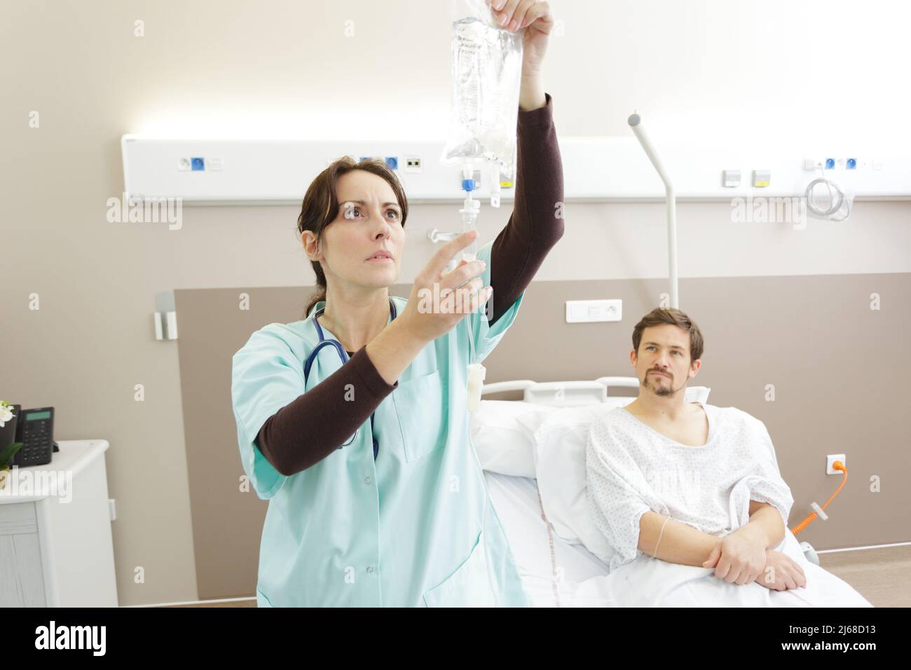 concerned nurse checking patients drip bag in hospital Stock Photo