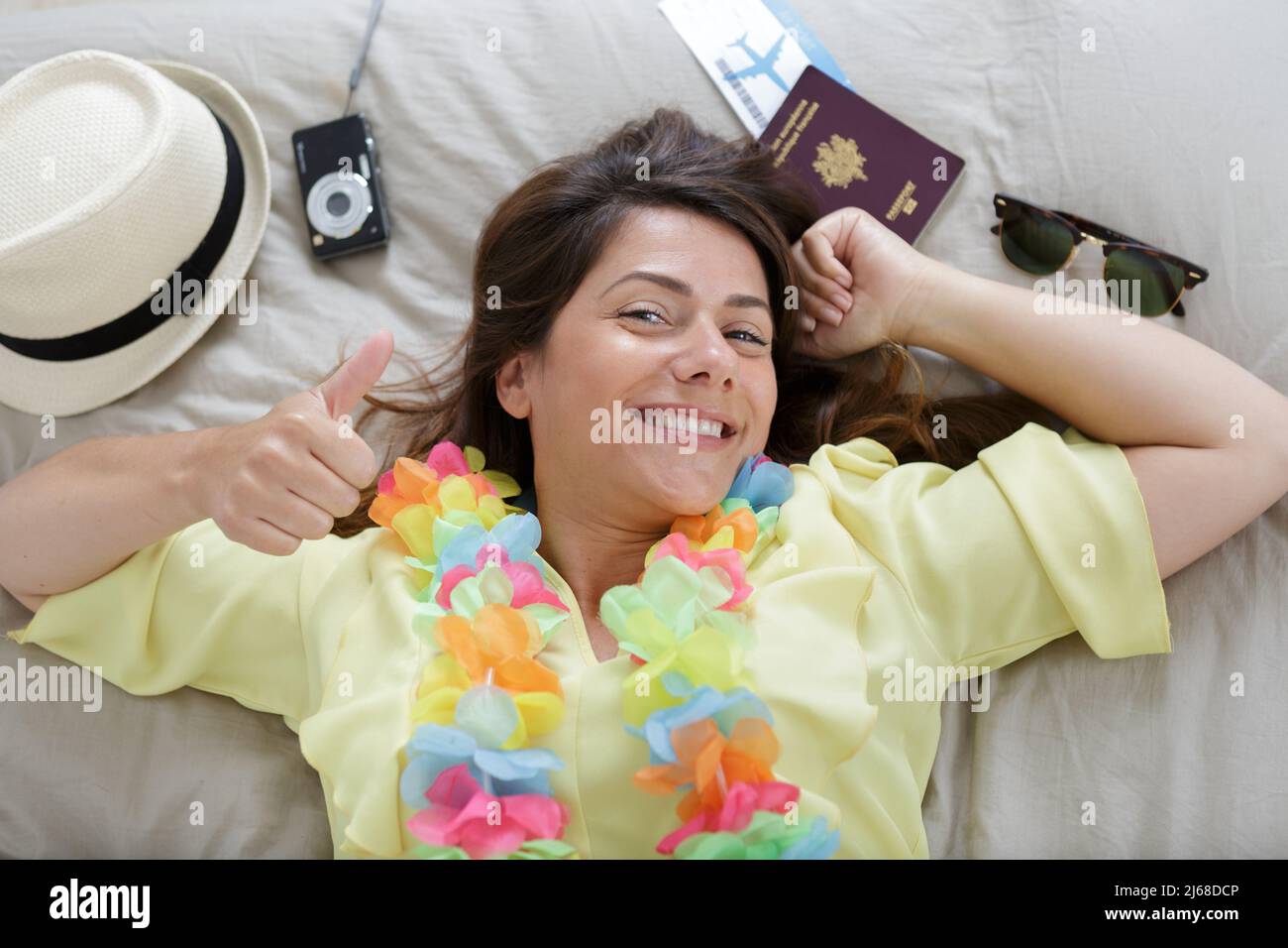 happy woman layed on bed surrounded by travel essentials Stock Photo ...