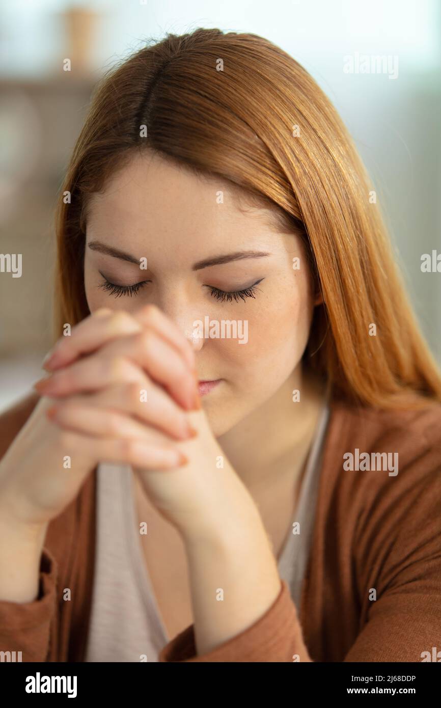 young woman at home with her eyes closed in prayer Stock Photo