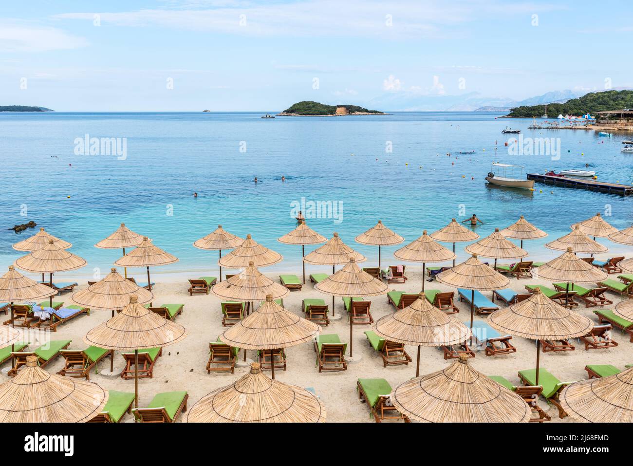 Ksamil, Albania - September 9, 2021: Umbrellas in rows on the Cocoa beach in the shadow of the clouds in Ksamil, Albania. Vacation concept background. Stock Photo