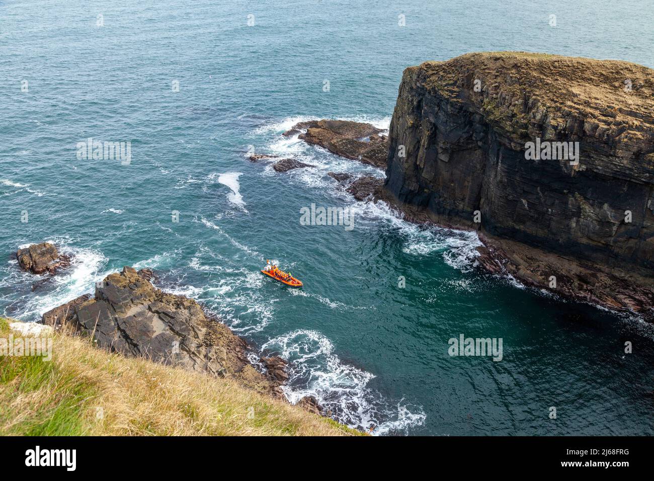 Whaligoe harbour with a rigid inflatable tourist boat viewing the cliffs Stock Photo