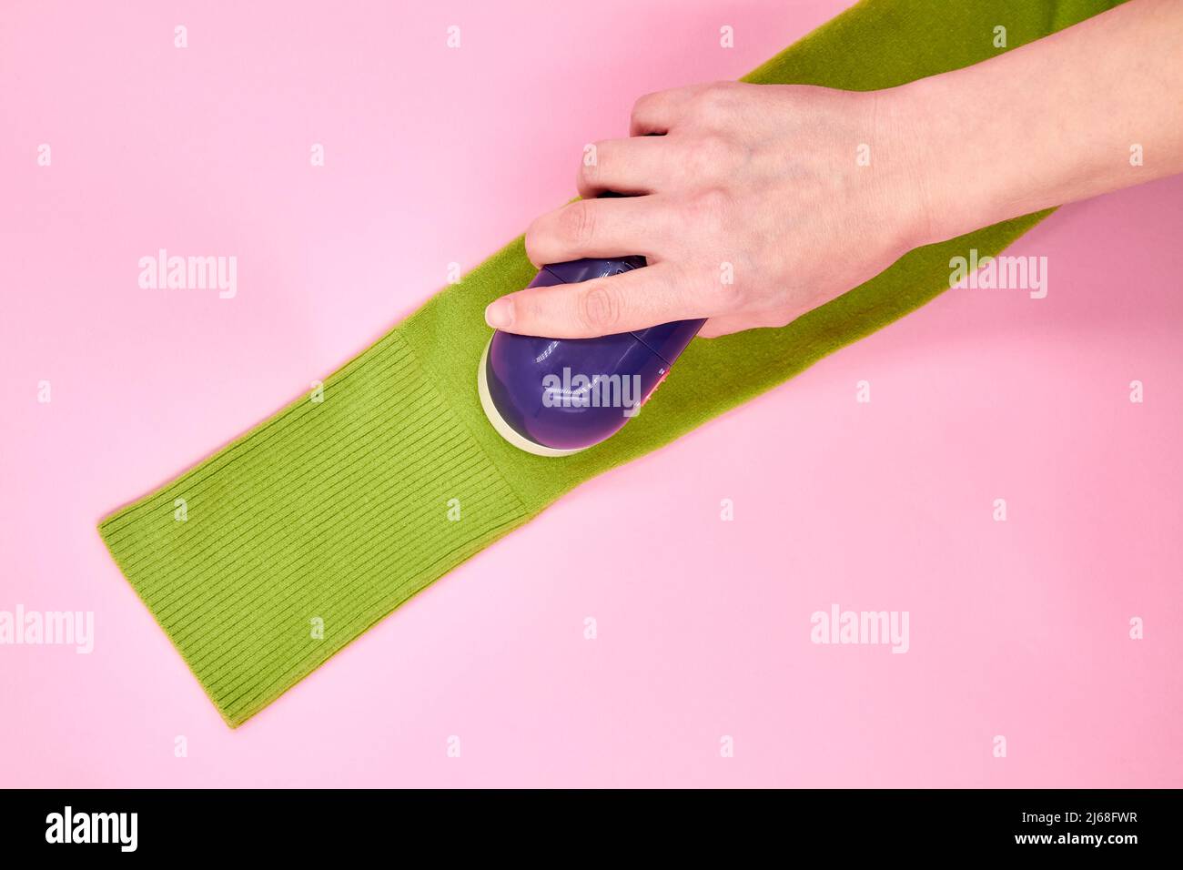 A wooman using Fabric shaver removes fabric pills from garments Stock Photo