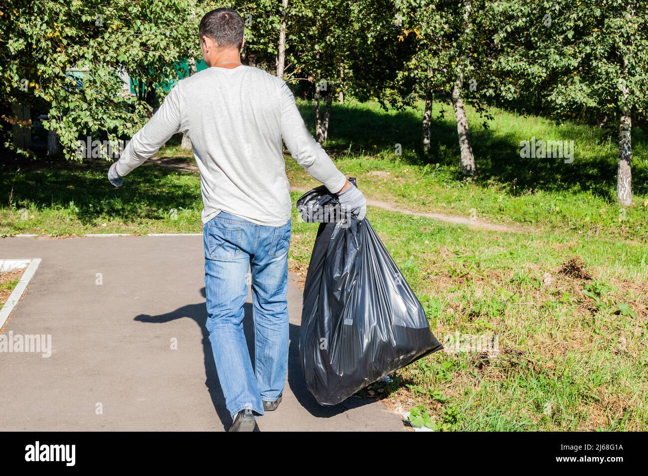 https://c8.alamy.com/comp/2J68G1A/the-man-takes-out-the-trash-garbage-collection-in-a-black-bag-the-guy-is-dragging-a-bag-with-something-collecting-plastic-on-the-street-2J68G1A.jpg