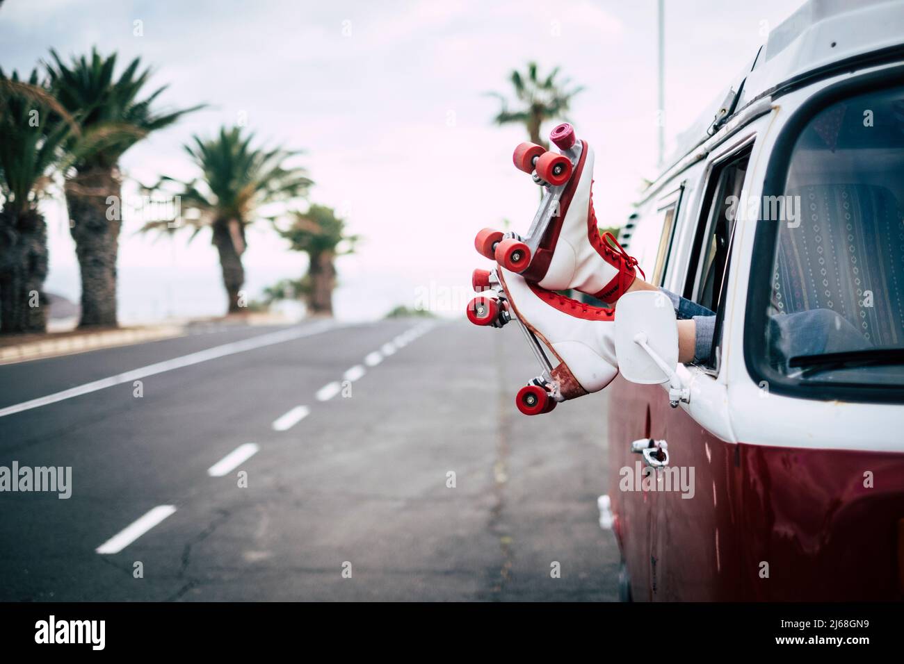 Travel and freedom concept with classic skate and van with long asphalt straight road in background. Old lifestyle alternative trendy. Red color. Peop Stock Photo