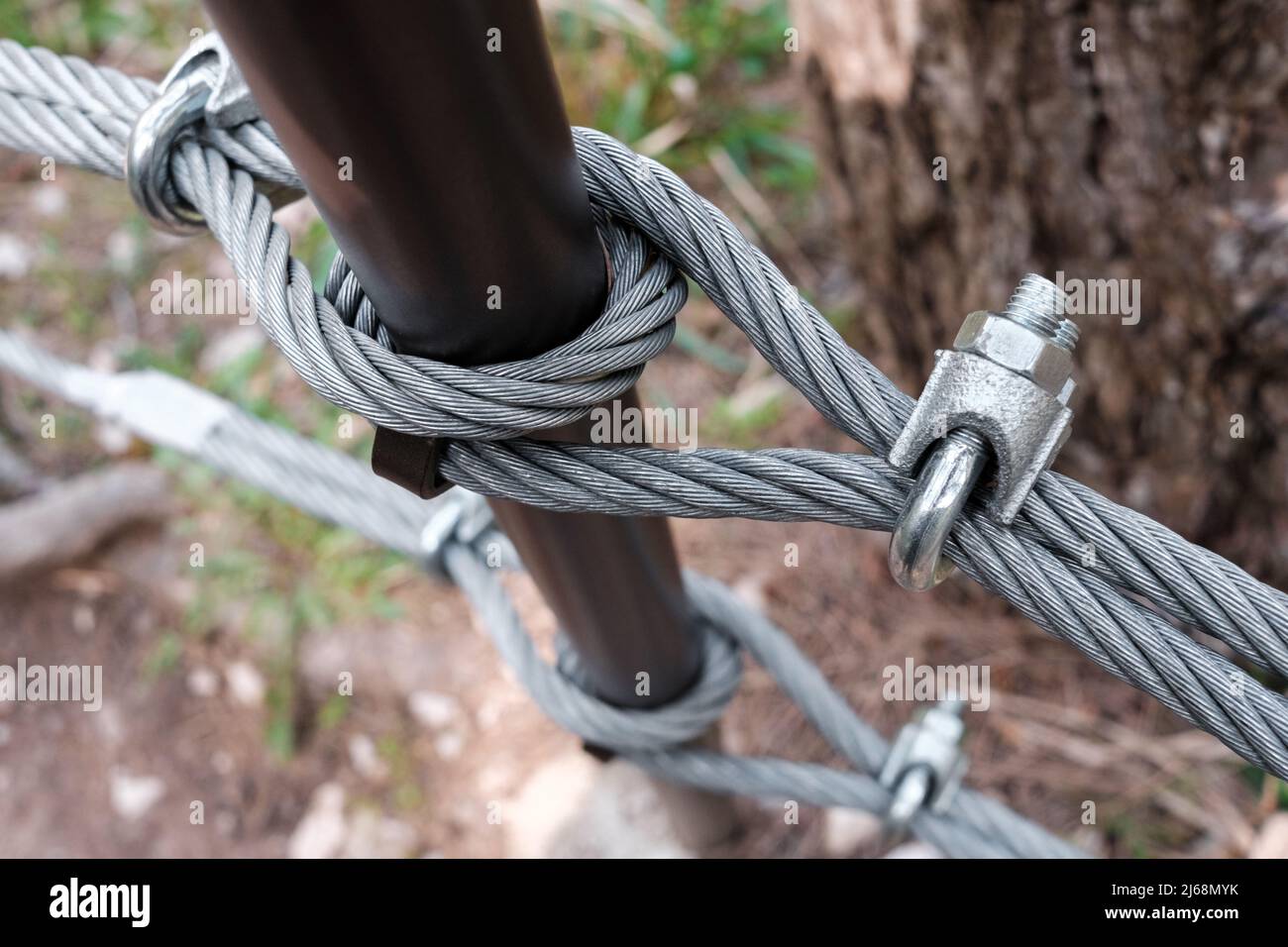 Interlocking steel cable secures a barrier on a mountain path Stock