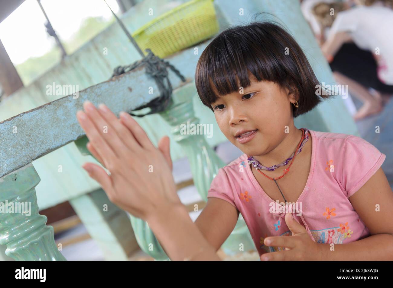 A volunteer student tourist playing a hand-clapping game with young girl at the Orphanage at Sangkhlaburi. Kanchanaburi. Thailand Stock Photo