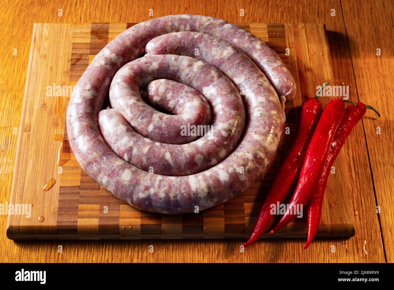 Raw sausages on a cutting board with red pepper Stock Photo
