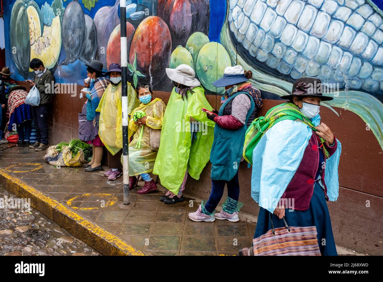 A Group Of Peruvian Women Standing In The Street During A Rain Shower