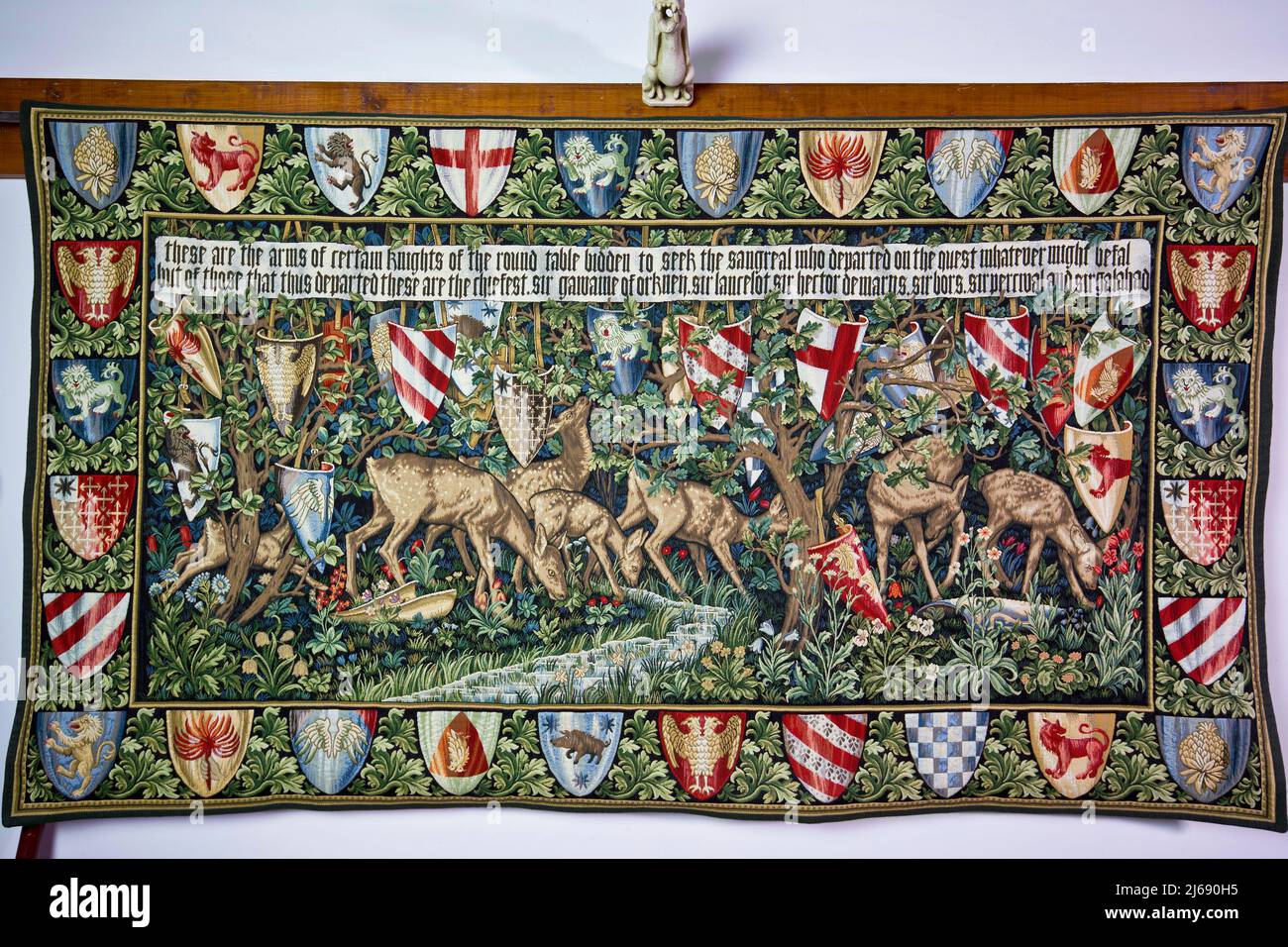 Tapestry created by 19th century designer William Morris, depicting the shields of King Arthur’s Knights hanging in trees, whilst a herd of deer graze. Stock Photo