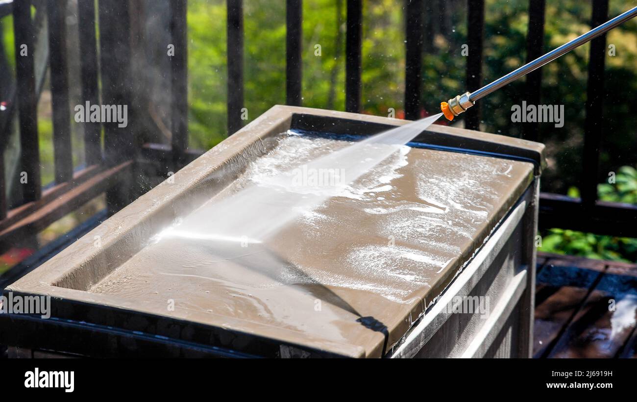 Cleaning plastic box on deck with pressure washer in springtime detail