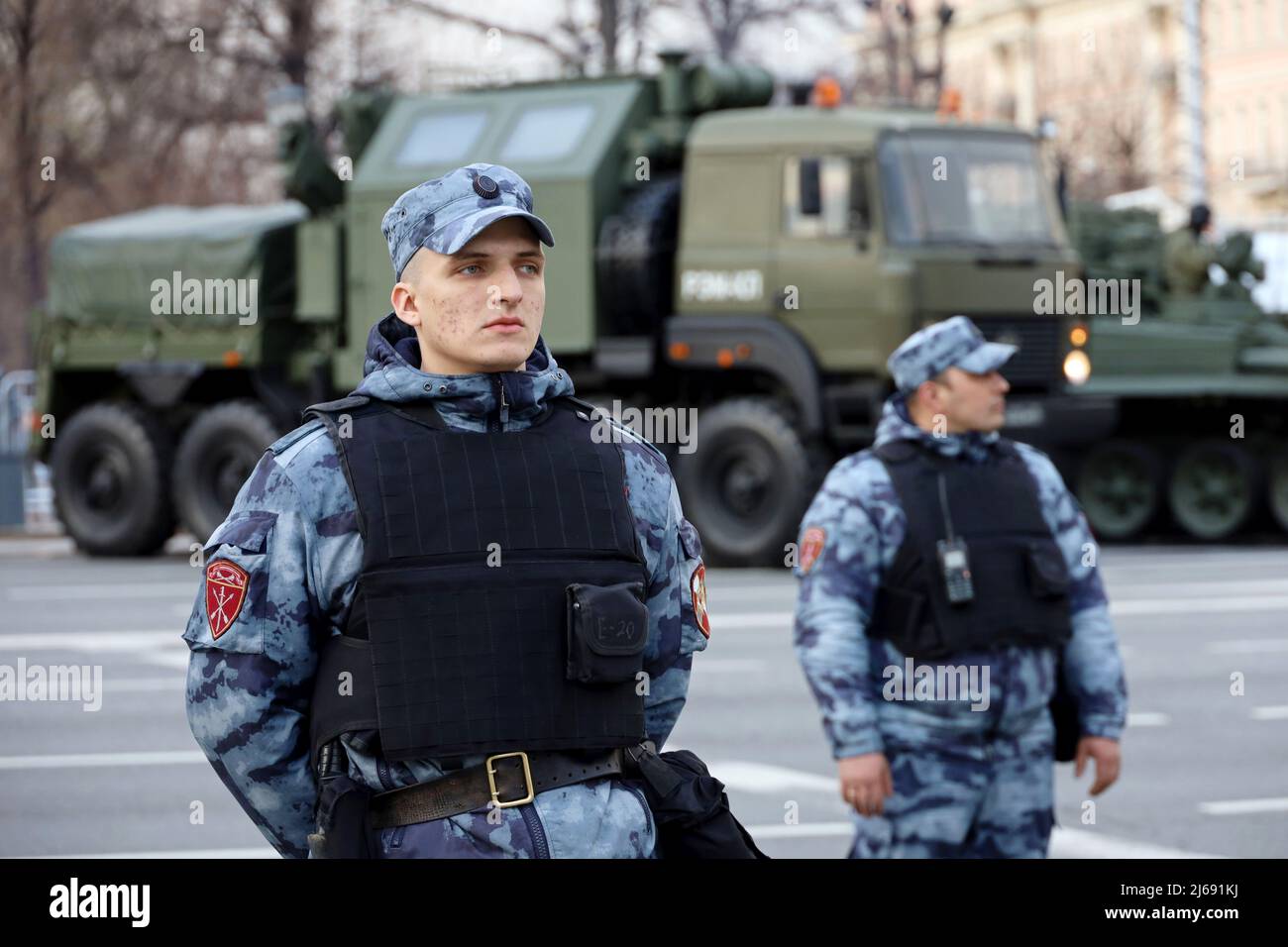 Soldiers of russian military forces of National Guard in bulletproof vest standing on background of armored vehicle Stock Photo