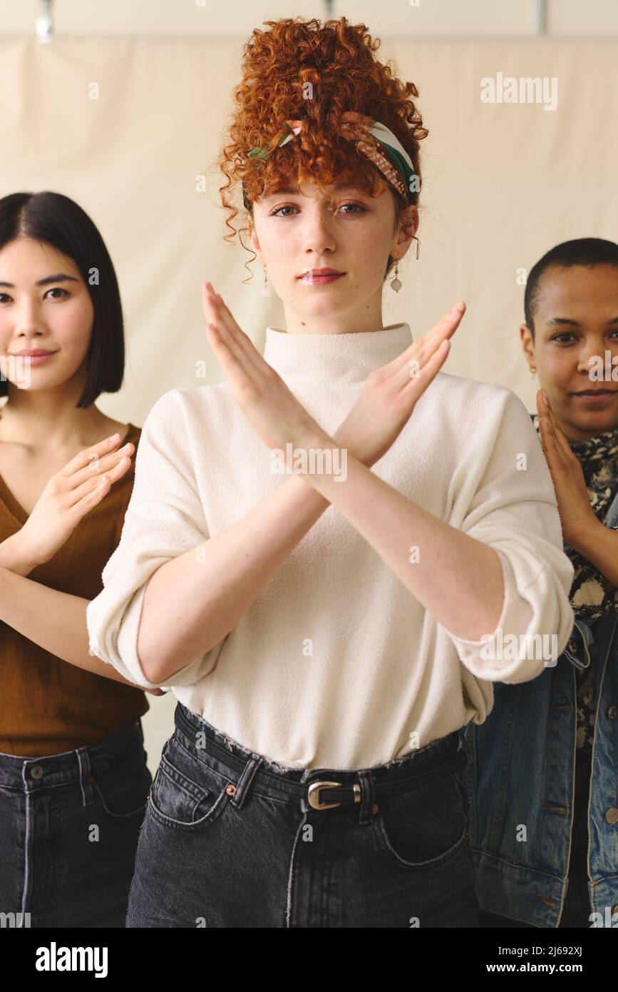 Young white woman gesturing Break The Bias in support of International Women's Day with multi ethnic female friends Stock Photo