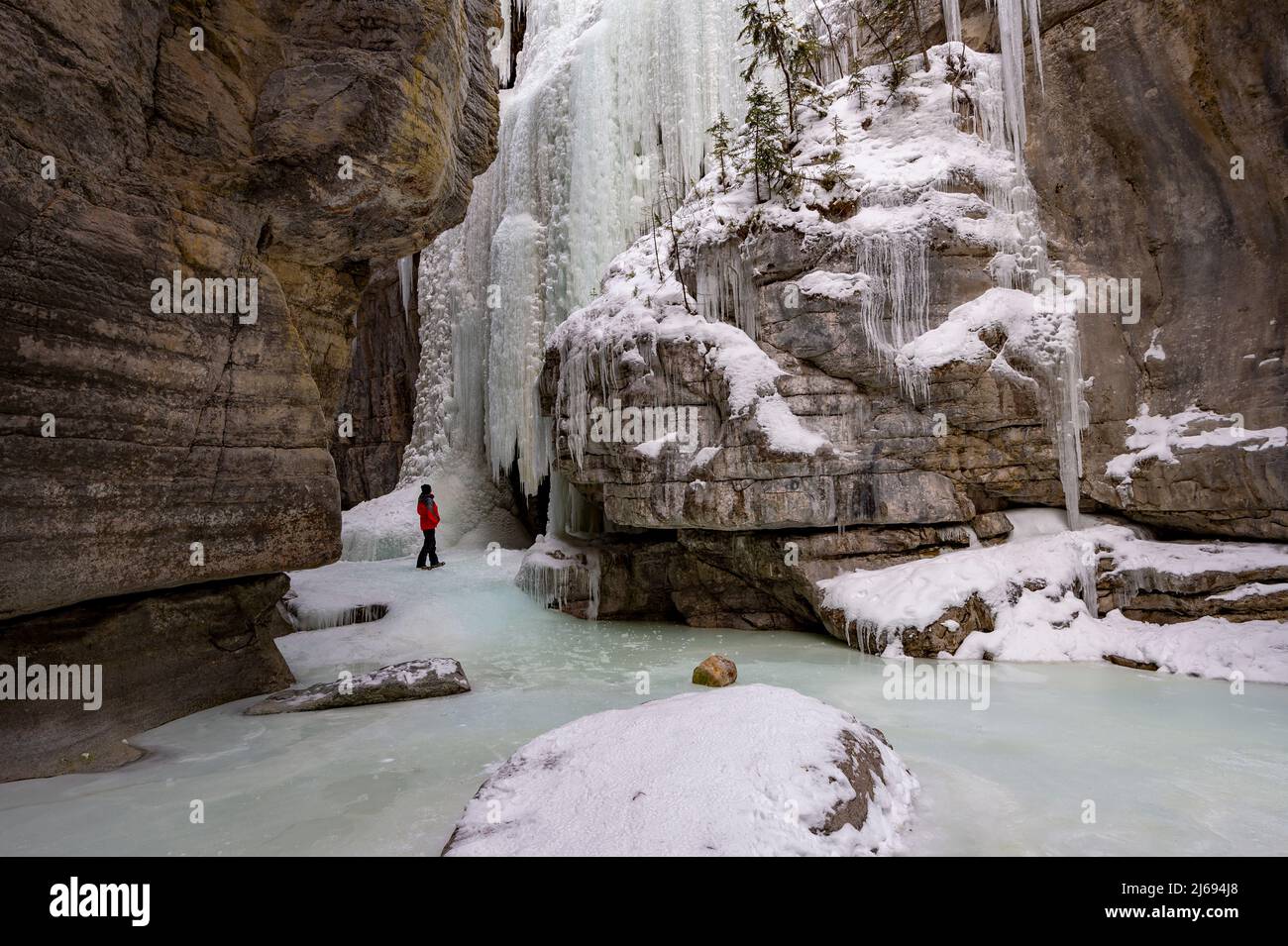A male wearing red coat stood in Maligne Canyon during winter conditions, Jasper National Park, UNESCO World Heritage Site, Alberta, Canada Stock Photo