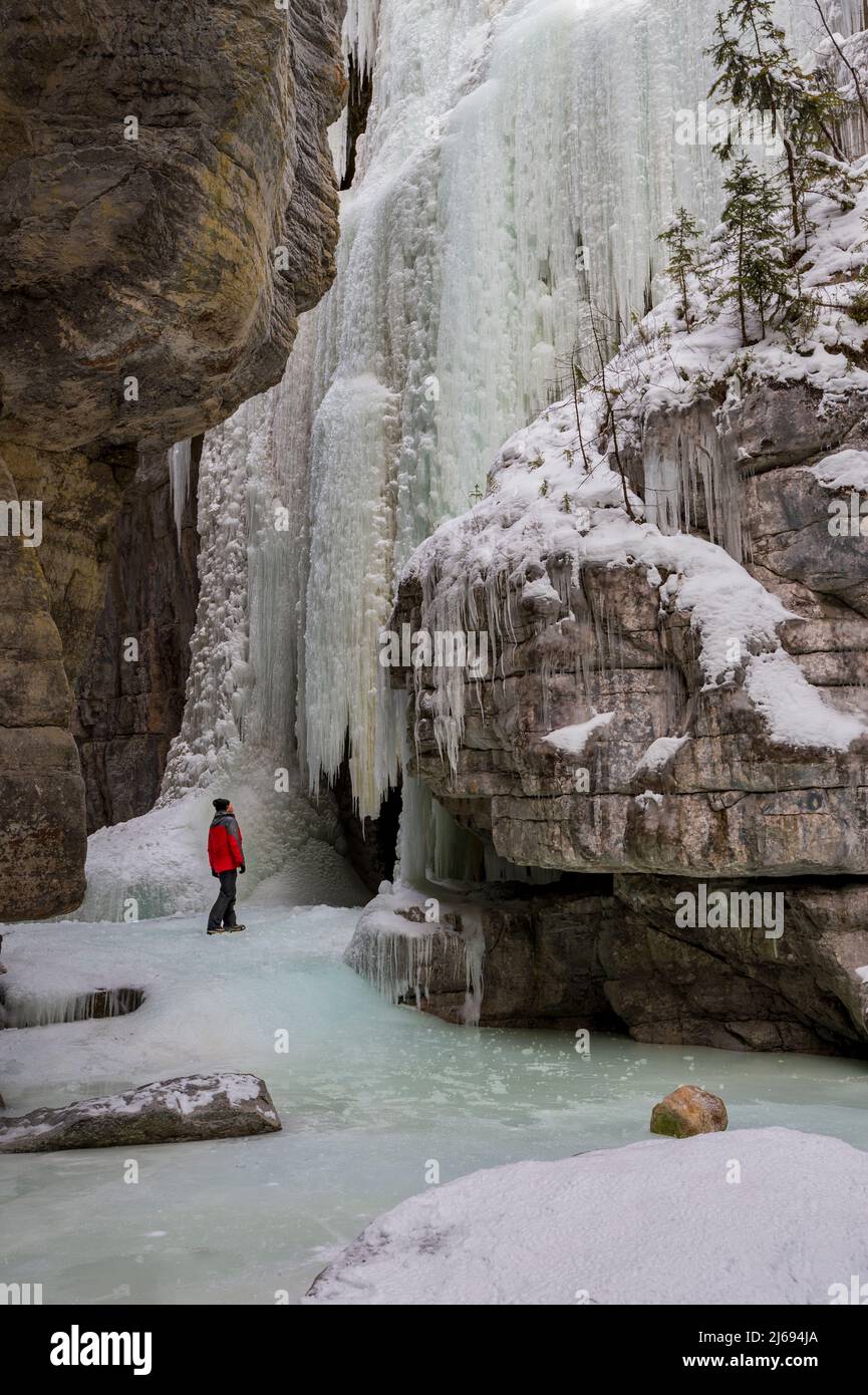 A man wearing red coat stood in Maligne Canyon during winter conditions, Jasper National Park, UNESCO World Heritage Site, Alberta, Canada Stock Photo