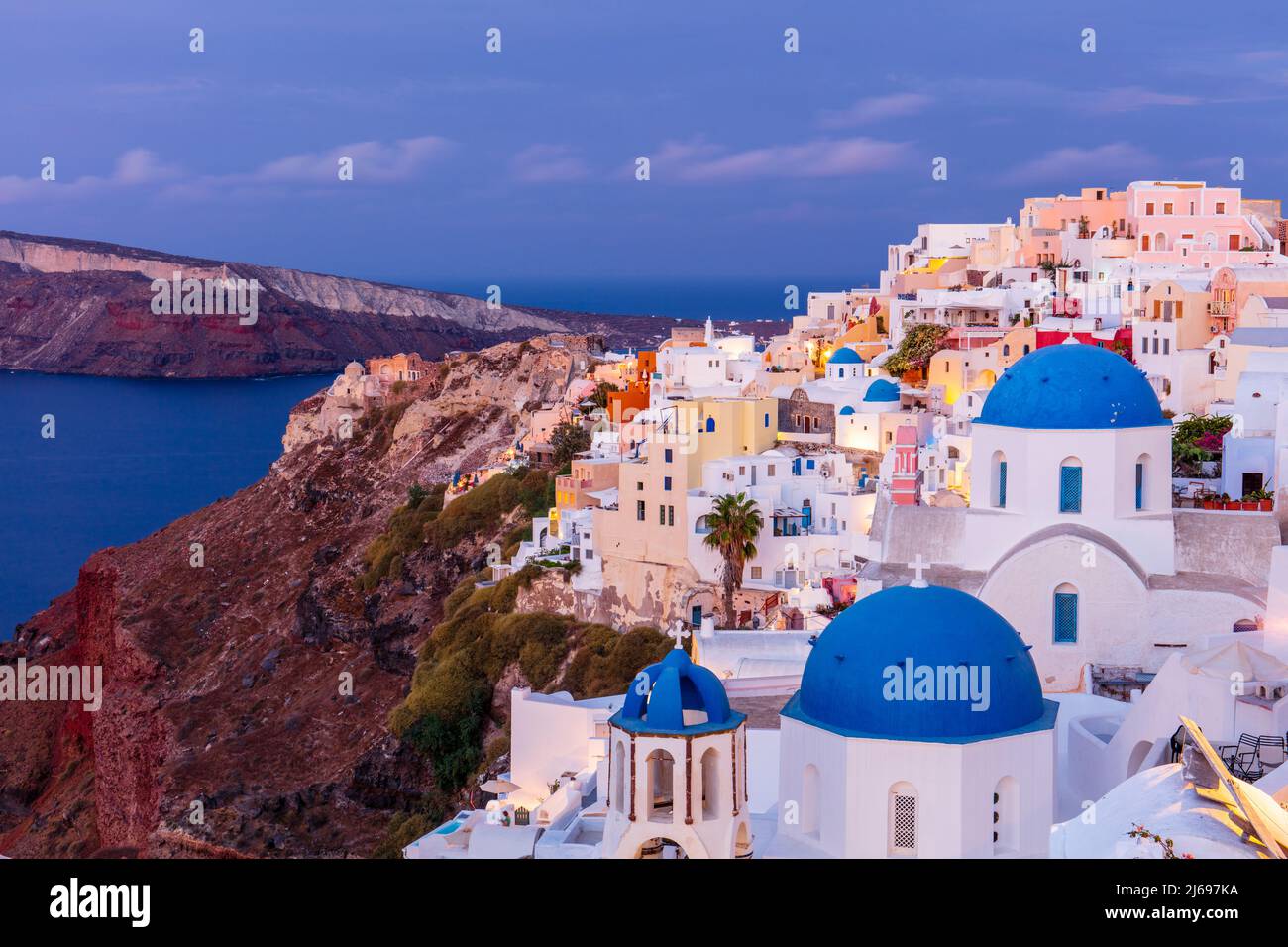 Blue domed white church and colourful buildings at sunrise, Oia, Santorini, Cyclades, Greek Islands, Greece, Europe Stock Photo