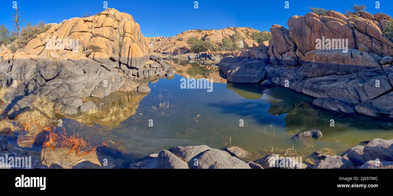 Reflective lagoon along East Bay Trail of Willow Lake, gray line on rock is where the water level used to be, Prescott, Arizona, United States of America Stock Photo