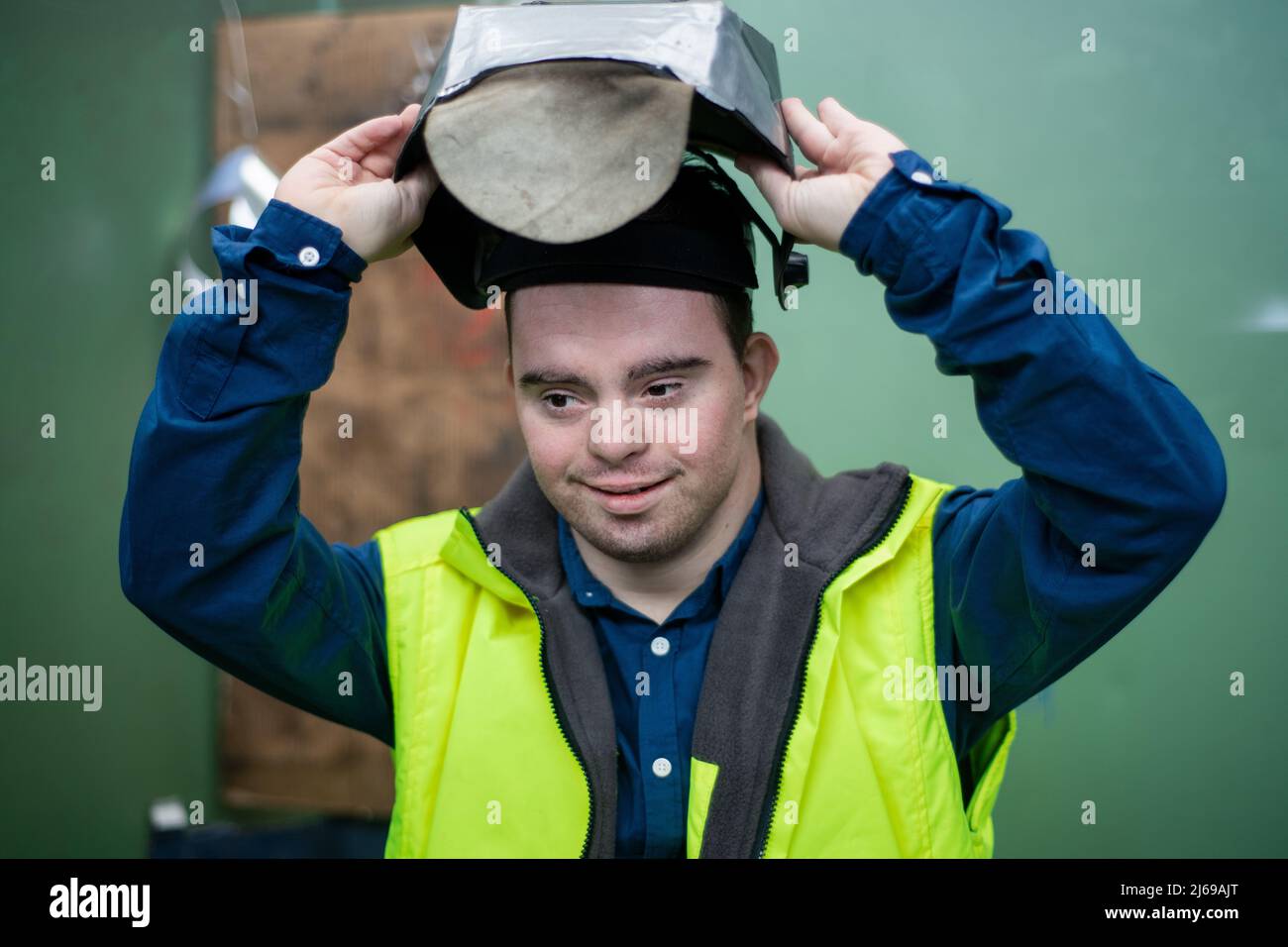 Young man welder with Down syndrome working in industrial factory, social integration concept. Stock Photo