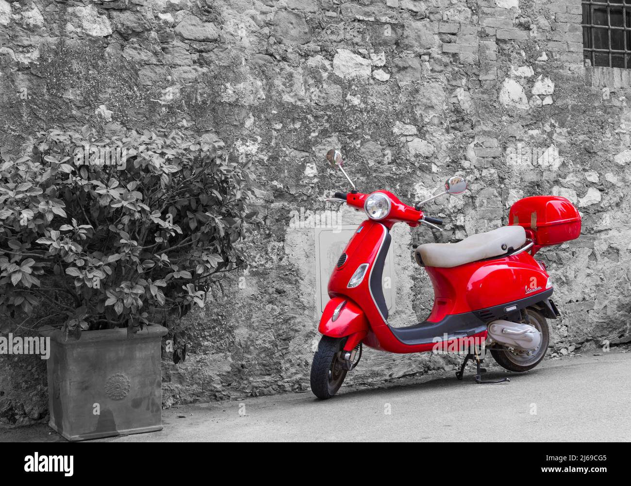Red Vespa scooter parked in street at Montisi, Siena, Tuscany, Italy in September - selective colour colouring, colour popping Stock Photo