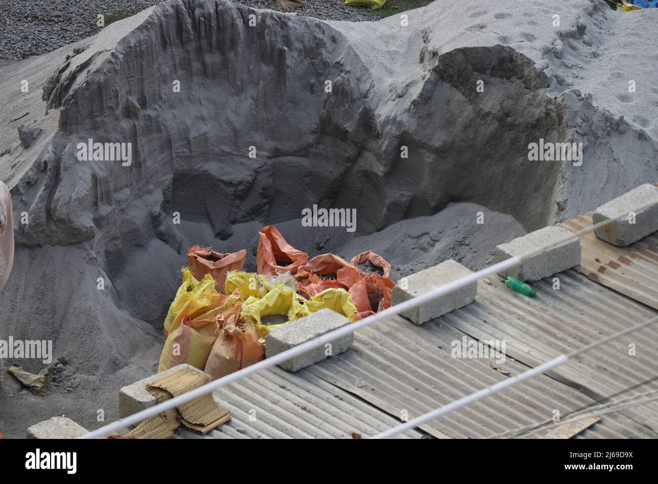 Pile of M sand and used cement bags filled with sand and concrete bricks on a construction area Stock Photo
