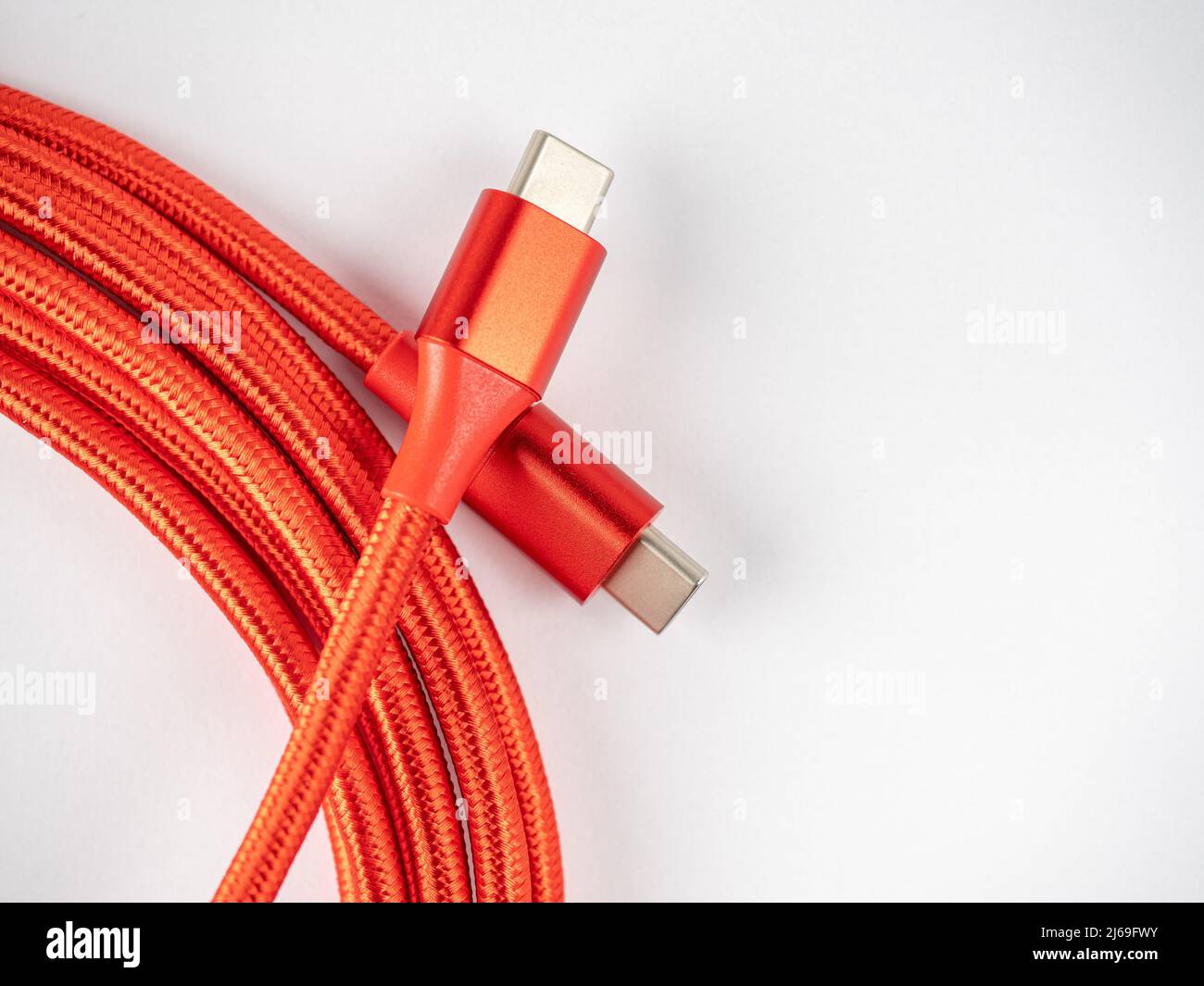 close up of a bright red USB type C to USB C cable isolated on a white background Stock Photo