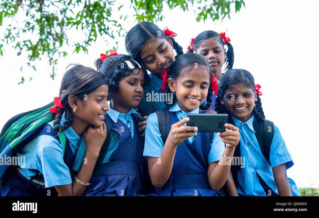 school girl kid playing video game on mobile phone while group of kids surrounded - concept of technology addiction, entertainment and togetherness. Stock Photo