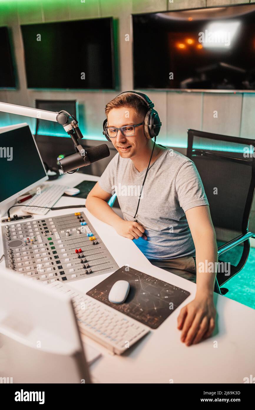 The DJ hosts the program and communicates with the audience on air at the radio station. The announcer reads the news. A male radio host speaks into a Stock Photo