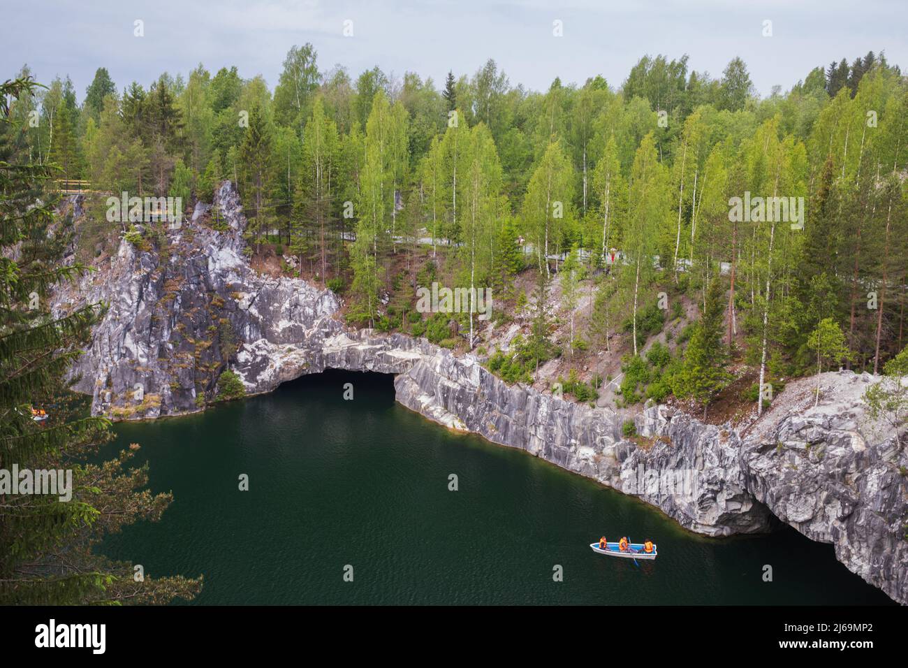 Karelian landscape with tourists in boat sailing the former marble quarry filled with groundwater. Ruskeala, Russia Stock Photo