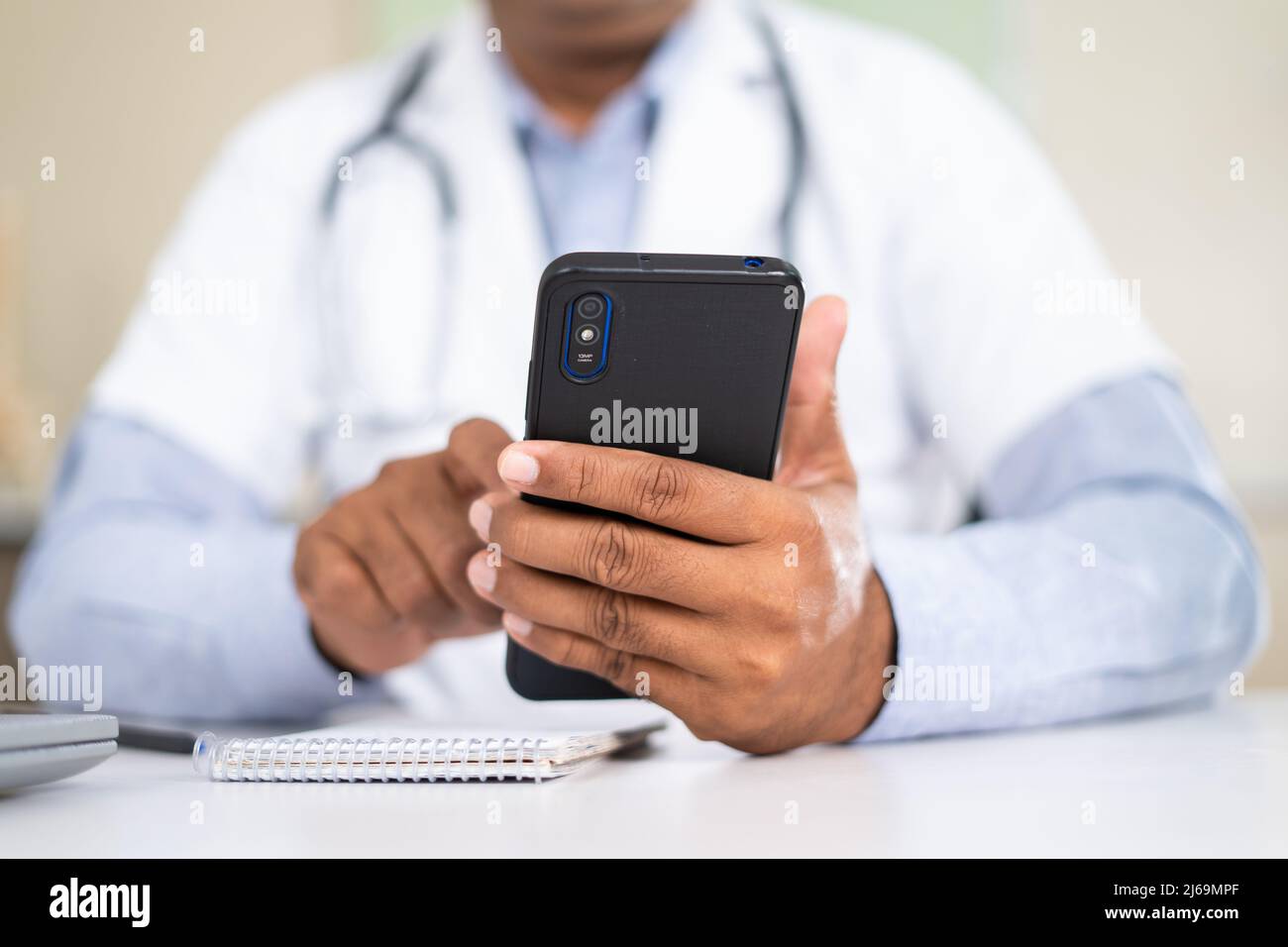 close up shot of doctor using mobile phone while at hospital - concept of virutal doctor consultation , taking break and healthcare service. Stock Photo