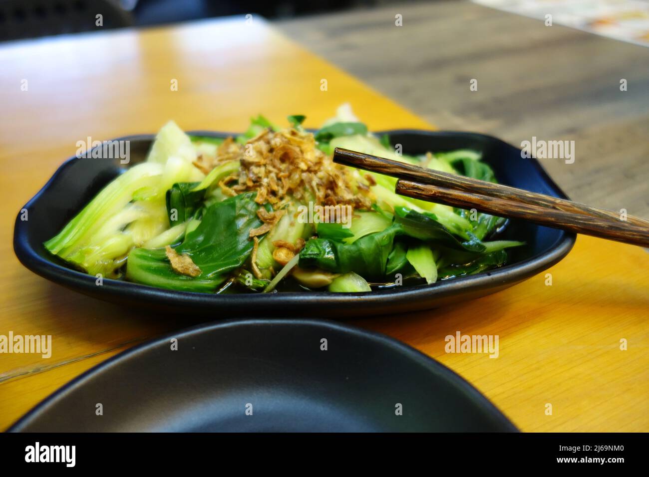 green vegetable on a black plate with wooden chopsticks as a close up Stock Photo