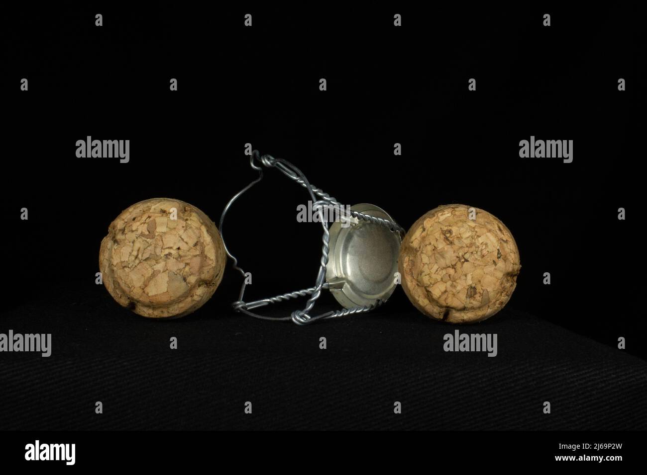two traditional sparkling wine corks and a single wire cage isolated on