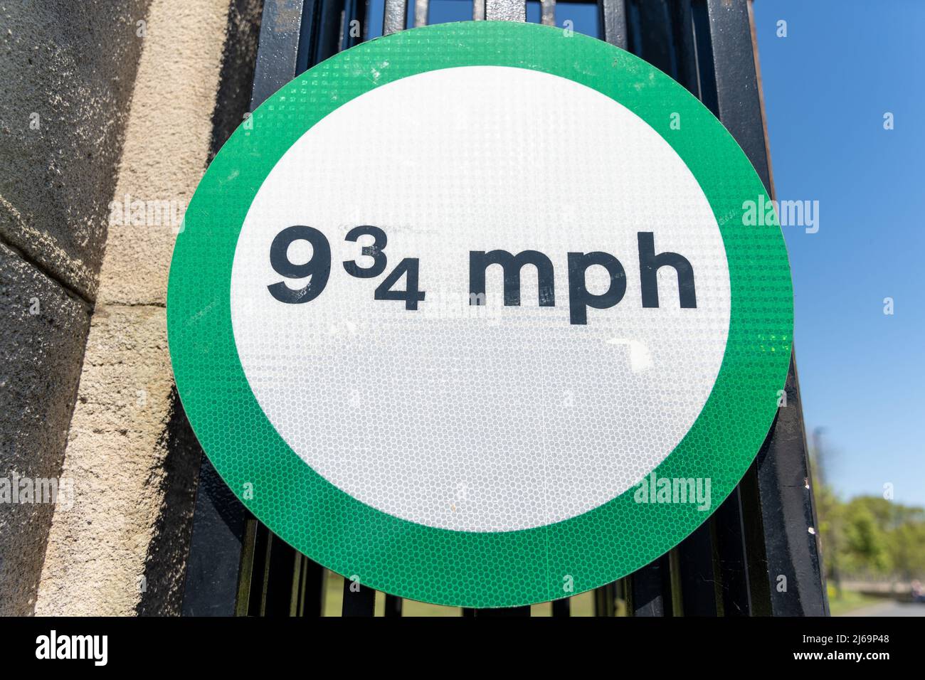 Unusual road sign for nine and three quarter miles per hour in a green circle, on the gate of Exhibition Park, Newcastle upon Tyne, UK. Stock Photo