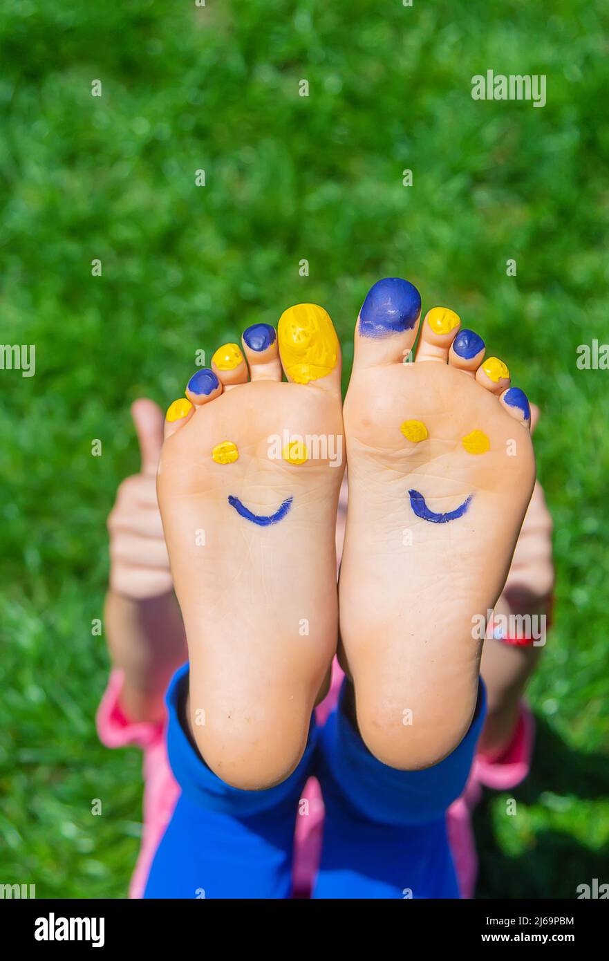 Child feet on the grass Ukrainian flag. Selective focus Stock Photo - Alamy