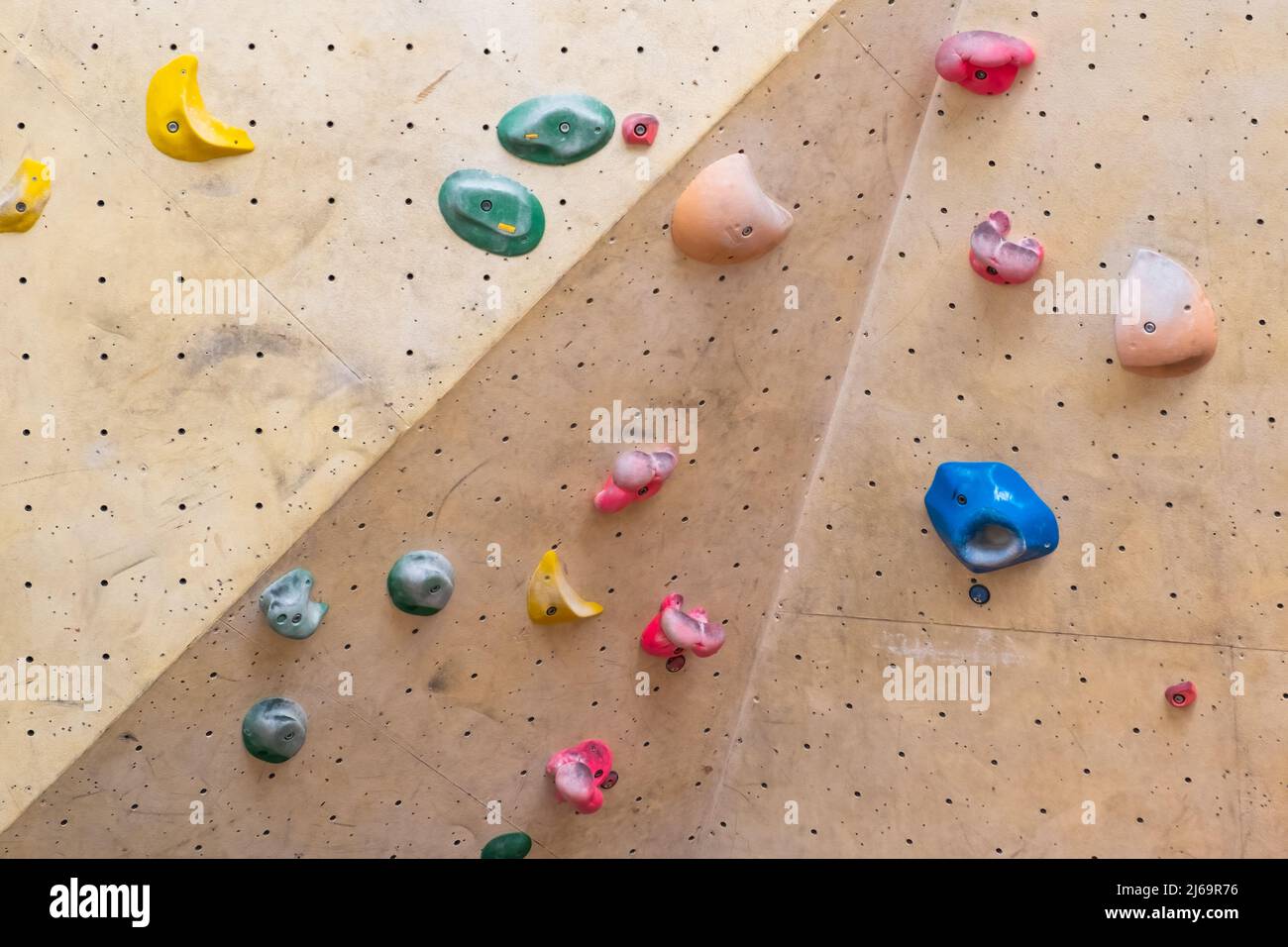 Artificial rock climbing wall with various colored grips. Stock Photo