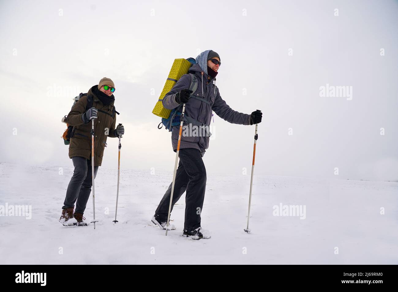 Men go after him during the polar winter expedition to the north. People in winter jackets with large backpacks. Winter climbing and expedition Stock Photo